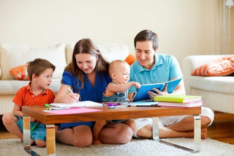 A young family, father, mother, two small children reading and playing at home, Finland,
