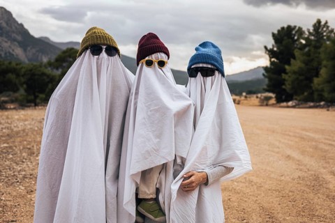Family dressed as playful ghosts outdoors celebrating Halloween. Creative homemade costumes,