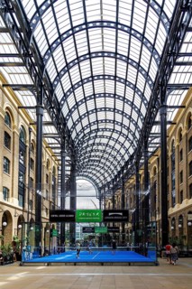 Sunlight filters through the barrel-vaulted glass and iron roof of Hay's Galleria, a former Thames