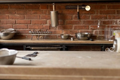 A neatly organized kitchen countertop featuring various metal cookware, including bowls and tools,