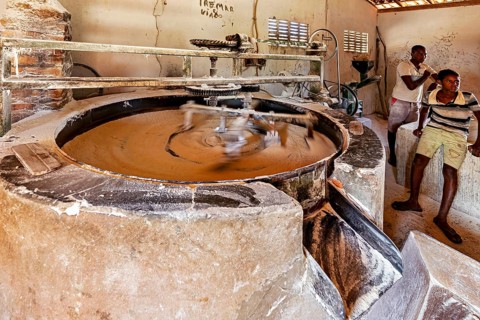 Two men working in a workshop with an old stone mill, a cassava mill in the Caatinga of Bahia and