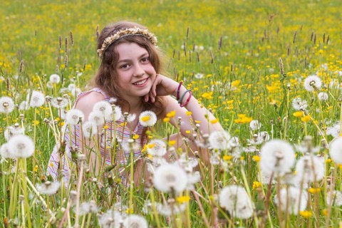 Portrait of a smiling girl sitting in a flower meadow, Mondsee, Salzkammergut, Austria