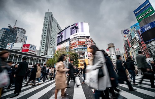 Crowd crossing zebra crossing on a large intersection, motion blur, back modern houses with