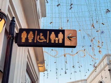 A directional sign points to restrooms for men, women, and accessible options, located in a public