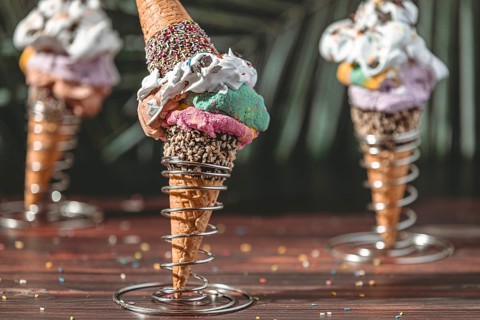Colorful ice cream in waffles in metal holders decorated with cream and sprinkles