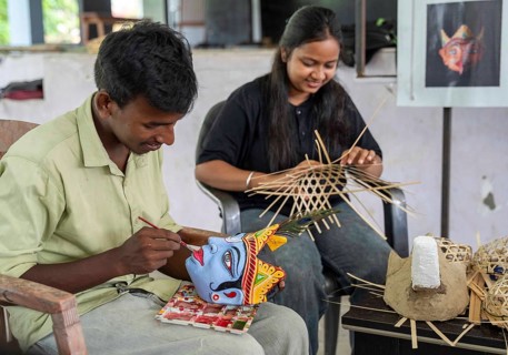 A student paints the facial details of a traditional mask at a mask-making workshop during an