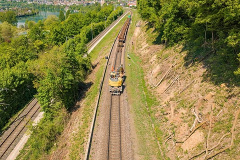 View of a railway line with a work vehicle and trees in natural surroundings, construction site by