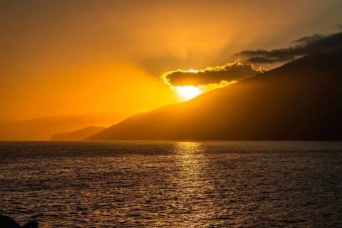 Ocean water reflecting the warm glow of a golden sunset behind el hierro island mountains, creating