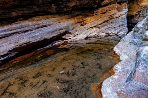 A shallow area filled with water in a rocky gorge surrounded by rocks, deep gorge in the spiny