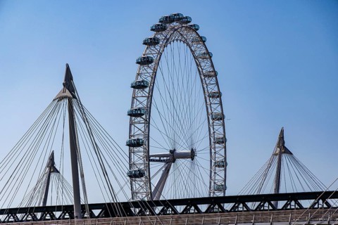 The London Eye observation wheel rises behind the suspension cables of the Golden Jubilee Bridges