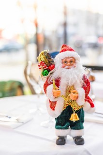 A festive table setting with a decorative Santa Claus figurine. The table is elegantly arranged