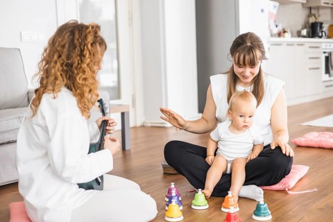 Two women and a baby interacting cheerfully in a room with musical elements