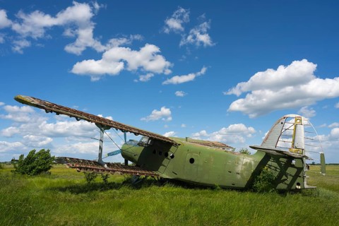 Abandoned old aircraft in a meadow under a clear blue sky, Antonov An-2 multi-purpose aircraft,