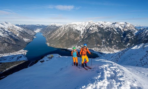 Picturesque view of Achensee and wintry mountain scenery, ski tourers, couple at the summit of