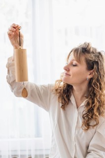 A woman smiling while holding a wooden chime, capturing a positive ambiance