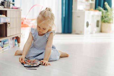 A young child sitting on a floor assembling a puzzle in a softly lit room