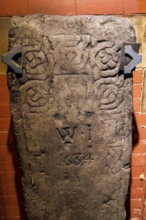 Recumbent grave slab decorated with carved roundel patterns and initials W I dated 1634, part of
