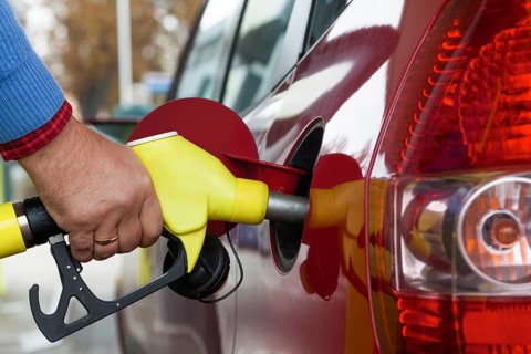 A young woman tank of gas at a gas station. Car costs are becoming more and more expensive due to
