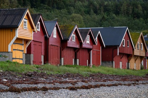 Red and yellow boathouses on a rocky beach, near Ålesund or Alesund, Møre og Romsdal Fylke, Norway