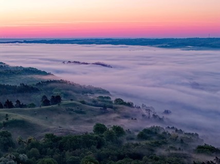 The hilly landscape of the Uckermark on the edge of the Oder Valley in morning light and fog above