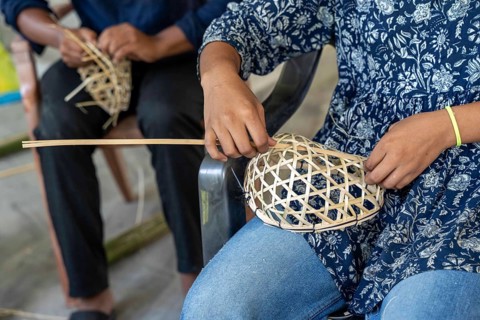 A student weaves a bamboo frame for a traditional mask in a traditional mask-making workshop during