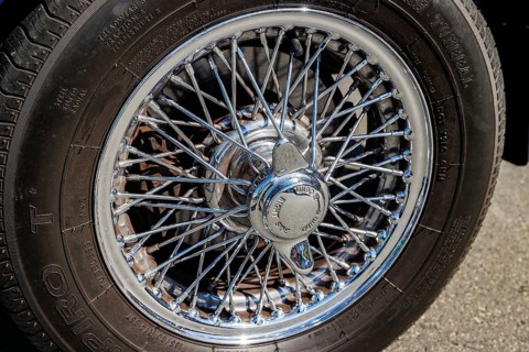 Chrome wire wheel and knock-off spinner hub of a classic MG sports car at a car meet