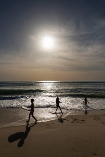 Silhouette of children playing against the evening sun on the Atlantic Ocean, France