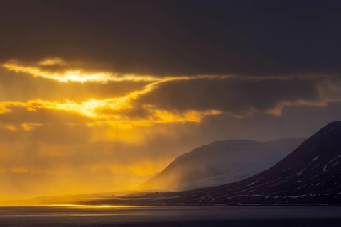 Isfjorden, Isfjord showing midnight sun at sunset with dark rain clouds in spring, Spitsbergen,