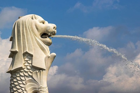 Against a blue sky the Iconic Merlion fountain spouting water designed with a lion head and fish