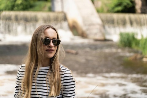 Portrait of a woman in a striped top and sunglasses in front of the dam by the river, A woman