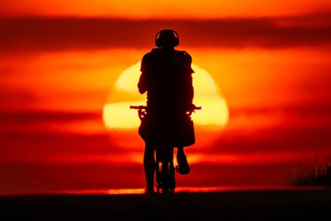 A cyclist rides towards the rising sun on a dirt road near Frankfurt am Main, Frankfurt am Main,