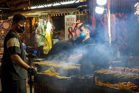Chef grilling satay skewers over charcoal at Satay Street street-food night market, Lau Pa Sat,