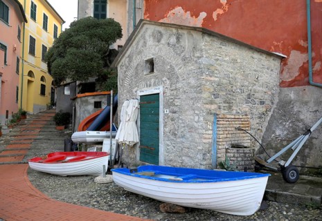 Rest in pre-season, folded umbrellas and fishing boats ashore in front of a building. Tellaro,