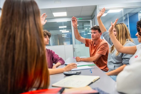 Young students in a modern classroom eagerly raise hands during an interactive lecture,
