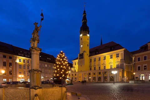 Town hall with decorated Christmas tree, fountain statue of Knight Dutschmann in front, dusk at the