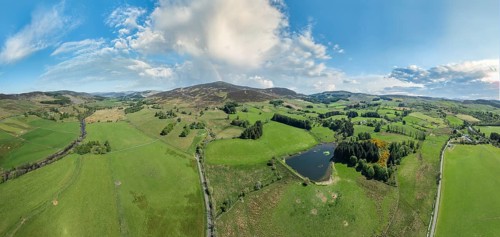 Aerial panorama photo of an agricultural landscape with meadows and pastures at the border of the