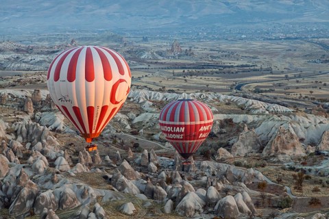 Two colorful hot air balloons float over spectacular valleys and mountains in Cappadocia in an