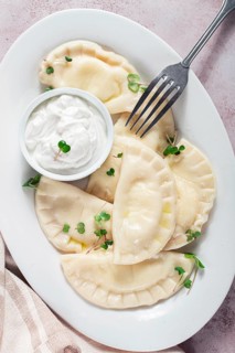 Traditional Georgian kvari dumplings, served with sour cream and herbs, close-up view, no people