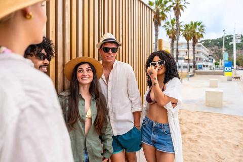 Diverse group of young adults laughing and chatting on a sunny seaside promenade, enjoying summer