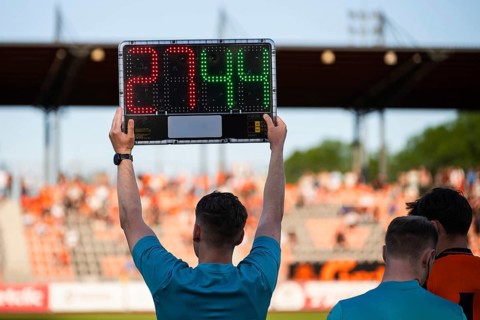 Assistant referee displaying substitution board during a soccer match with stadium crowd in the