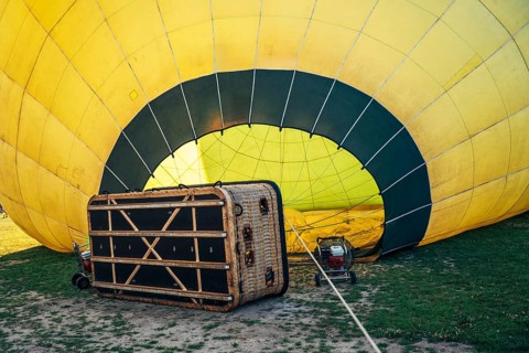 Partially inflated yellow hot air balloon and passenger basket on grass, close-up view, A yellow