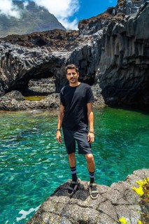 Man standing on volcanic rock by the emerald water of charco azul in el hierro, spain, enjoying a