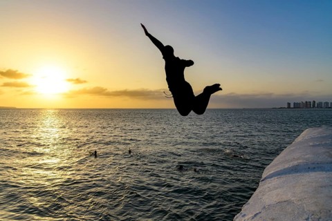 Young person jumping into the sea at sunset in Sao Luis, the capital of Maranhao