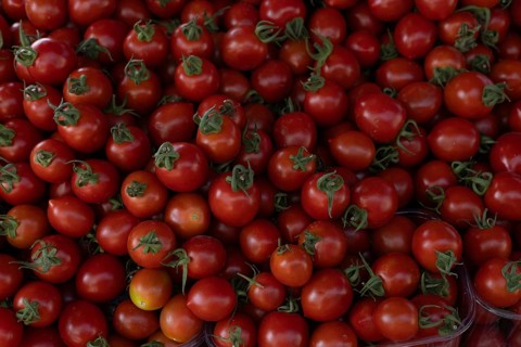 A pile of vibrant red cherry tomatoes with green stems