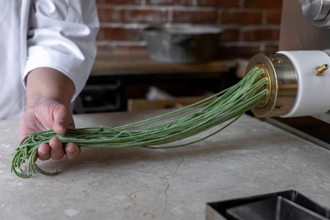 Process of woman preparing handmade pasta. Woman's hands working with dough to make pasta. Chef