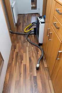 Professional water damage repair Drying equipment and hoses for underbody drying on wooden floor