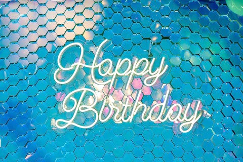 Colorful background with a neon sign that reads 'Happy Birthday'. The design features a shimmering,