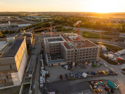 Construction site of a building at sunset, surrounded by cranes and building materials, new