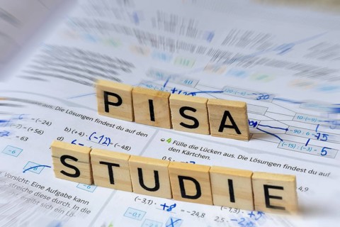 Wooden letters on a math textbook indicate the word PISA STUDY
