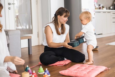 A music lesson with a toddler being taught how to play a ukulele